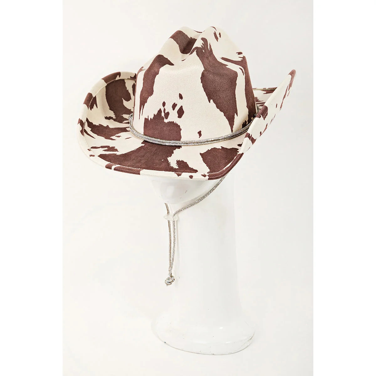Cow Print Draw String Cowboy Hat with brown and white cowhide pattern on glass