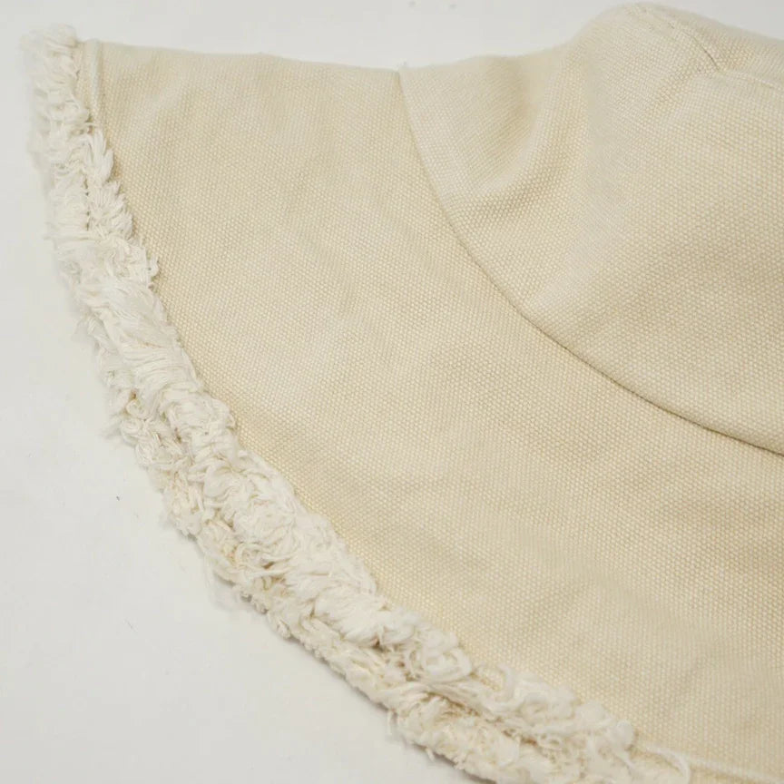 Cream-colored fringed bucket hat for stylish protection in the Keanu Twill Raw Edge design