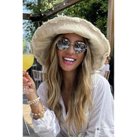 Smiling woman in a floppy bucket hat and sunglasses enjoying sunny weather