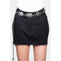 Black denim mini skirt styled with an ornate metallic oval chain belt and turquoise conchos