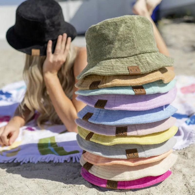 Stack of colorful bucket hats including a green terry cloth bucket embracing retro vibes.