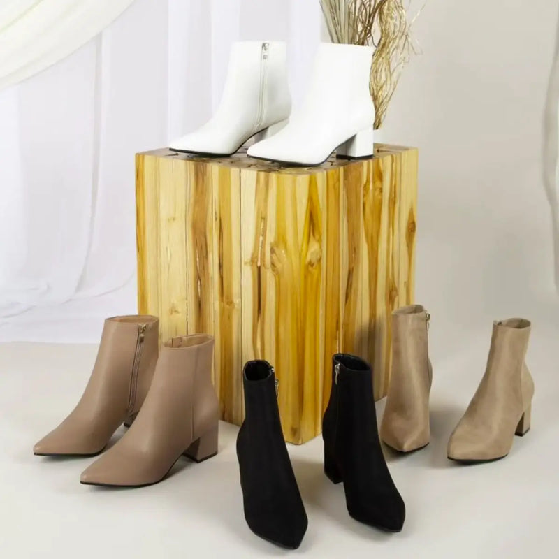 Gold-colored cylindrical pedestal showcasing stylish women’s booties from Del Mar.