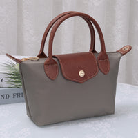 Medium luxe top handle crossbody bag in taupe with brown trim and zip top hardware
