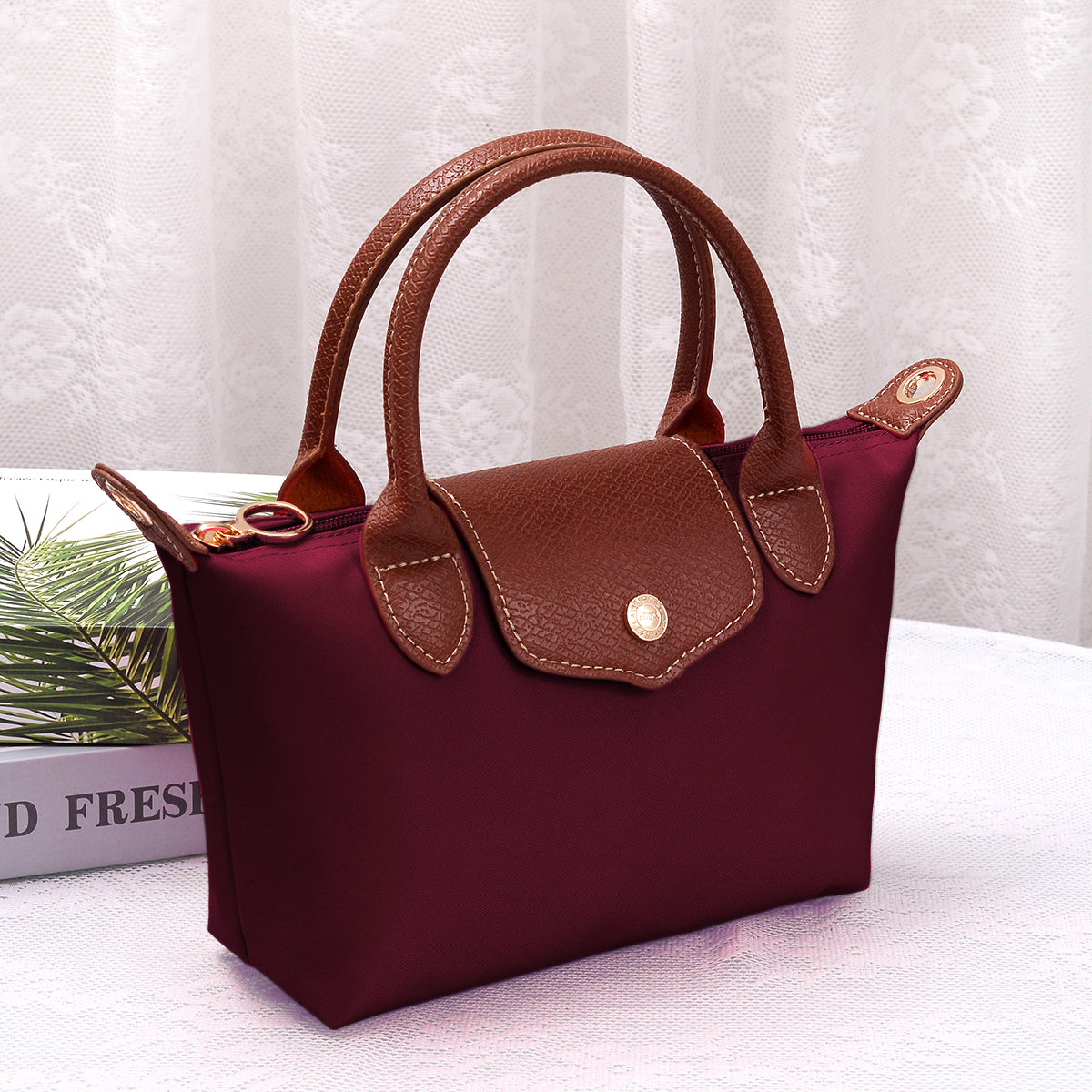 Medium luxe top handle crossbody bag in burgundy with brown trim and zip top hardware