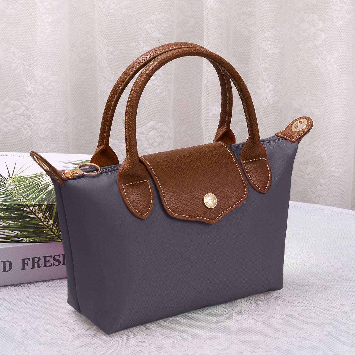 Medium luxe top handle crossbody bag in dark navy with brown trim and zip top hardware