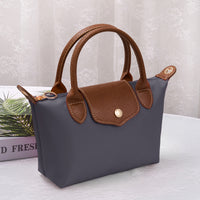 Medium luxe top handle crossbody bag in dark navy with brown trim and zip top hardware