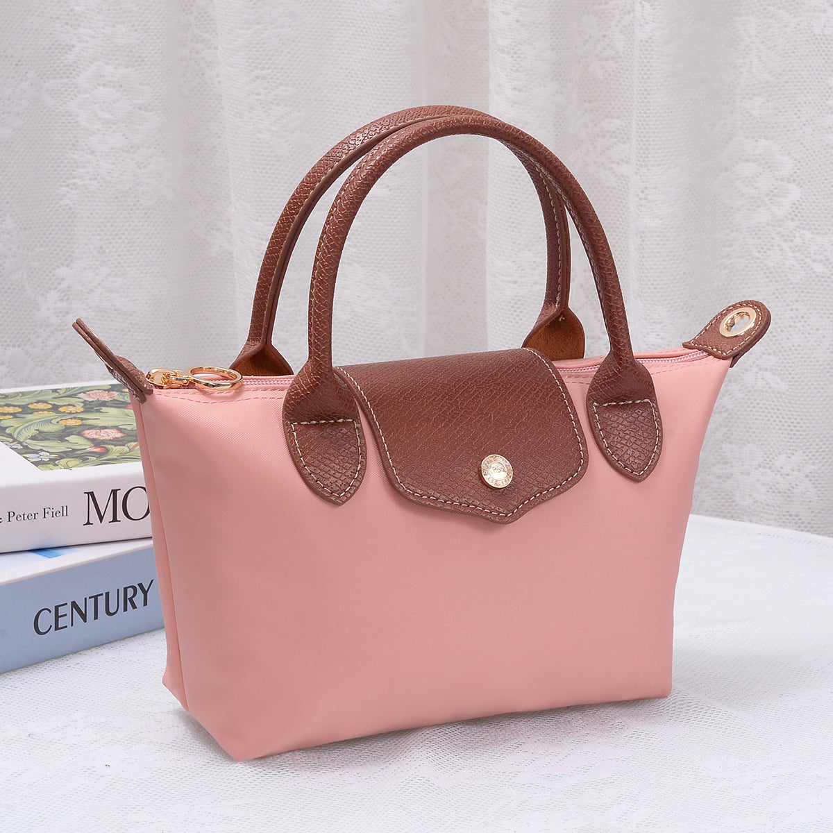Medium luxe top handle crossbody bag in blush pink with brown trim and zip top hardware