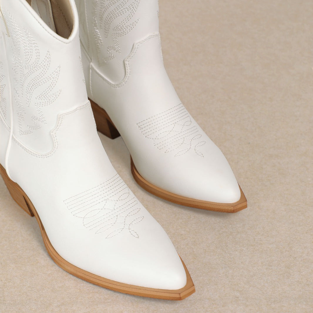 White cowboy boots with brown soles on a beige background
