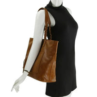 Brown leather tote bag with shoulder straps and zippered pocket on mannequin torso