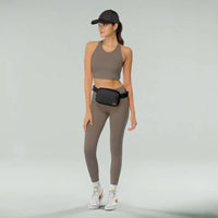 Woman in taupe athletic wear with a fanny belt bag and white sneakers