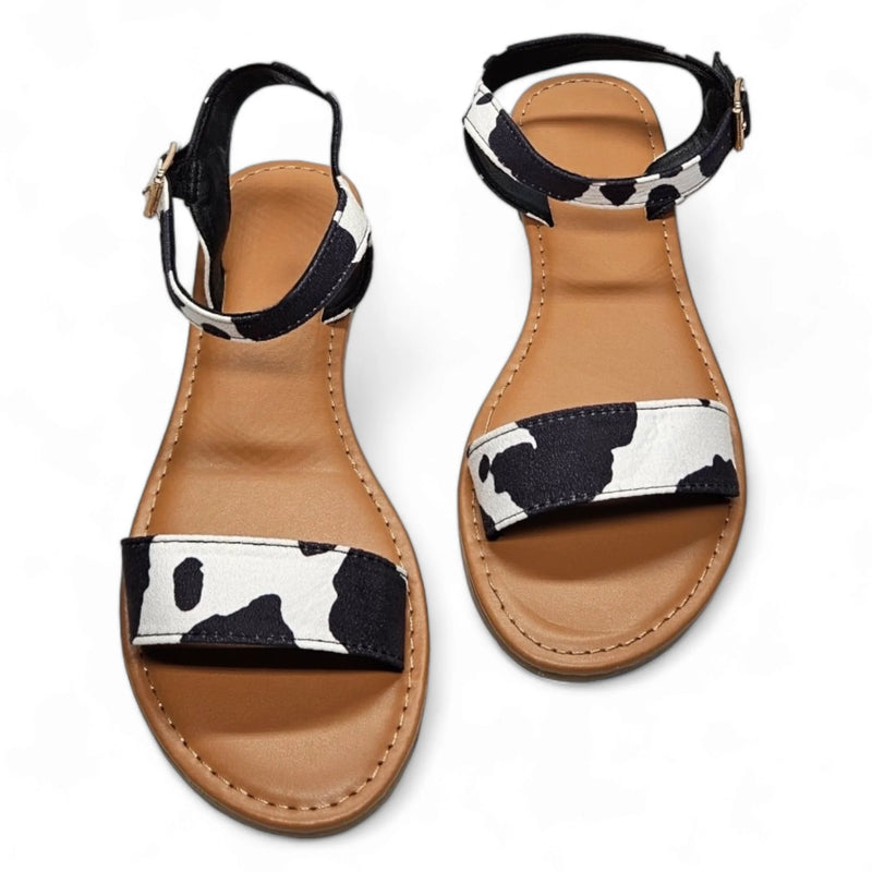 Cow Print Sandal featuring stylish black and white cow print straps and tan soles