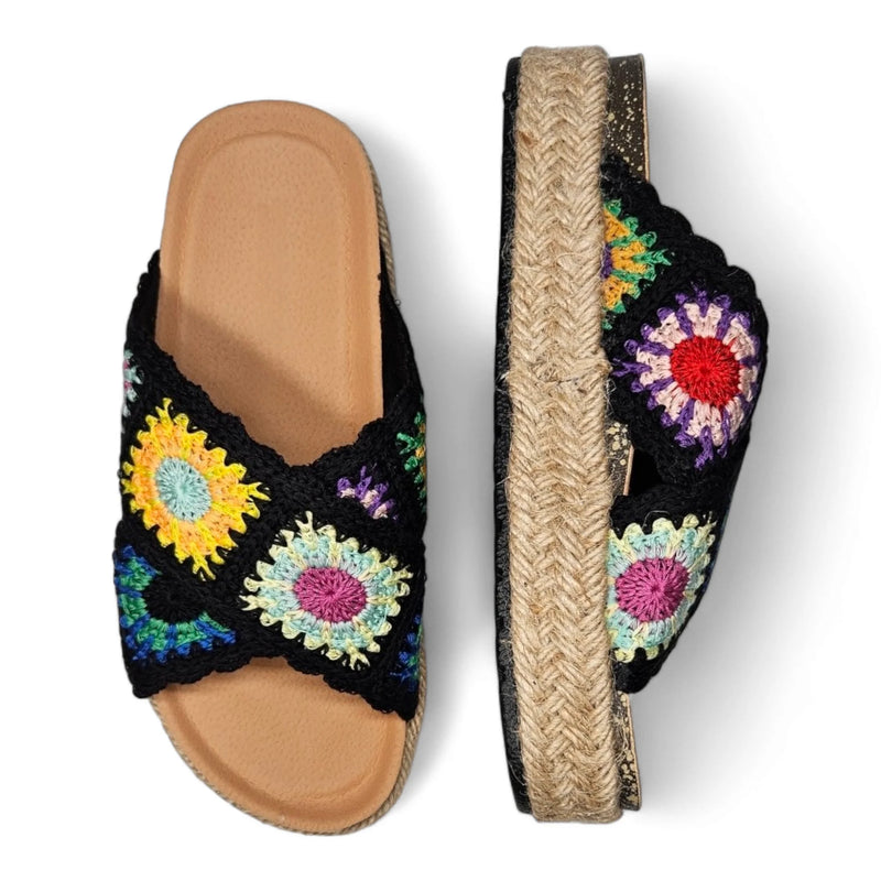 Colorful crocheted sandals with floral patterns on black fabric and tan soles