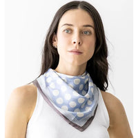 Light blue polka dot silky neck scarf styled over a white sleeveless top