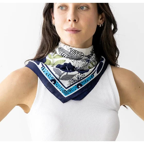 Patterned silk flower print scarf with navy border elegantly worn around the neck