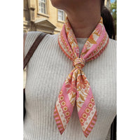 Person wearing a patterned pink and orange scarf on a blurred background