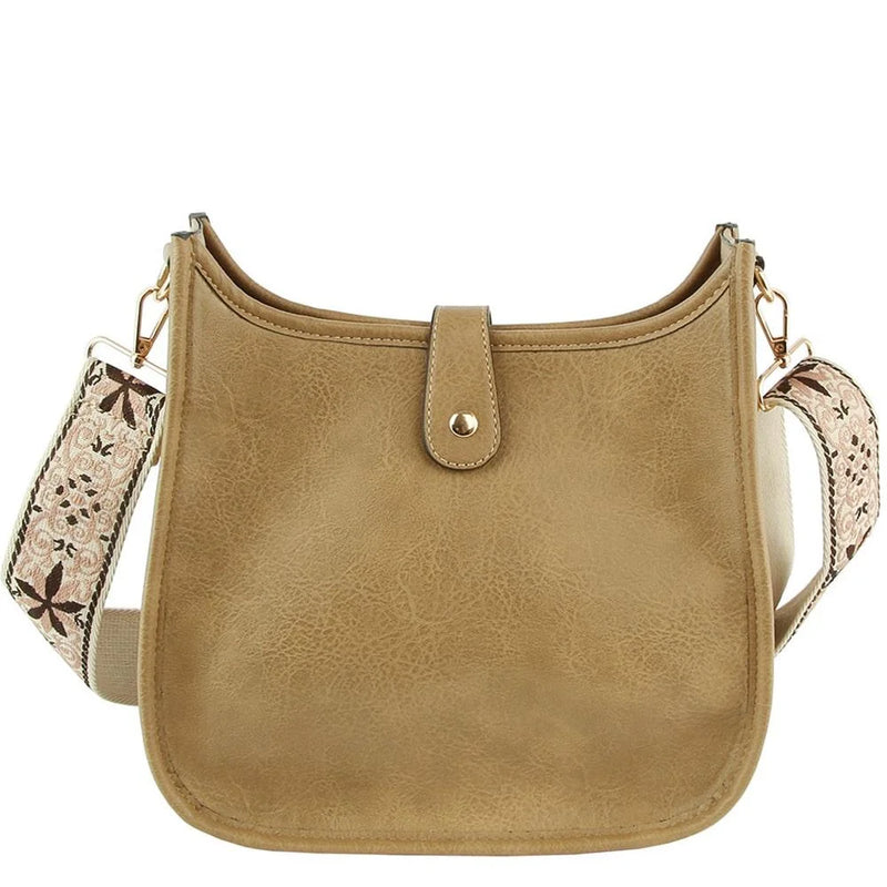 Tan leather hobo crossbody bag with a stylish patterned guitar strap