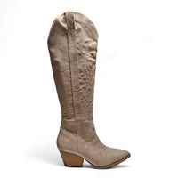 Tall beige knee high cowgirl boot featuring a pointed toe and stacked heel