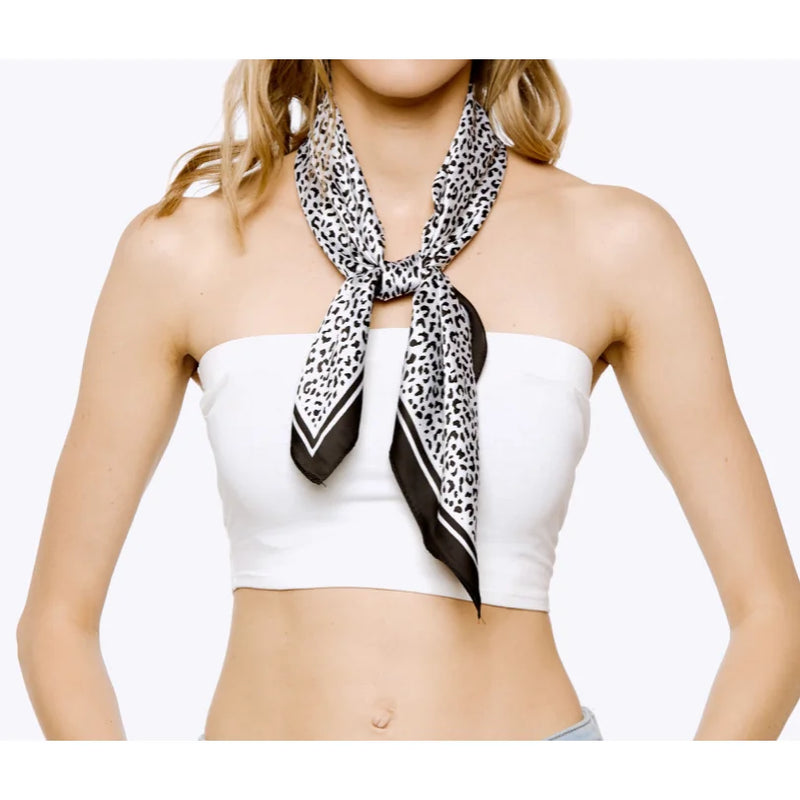 Leopard print silky bandana elegantly tied around a woman’s neck over a white top