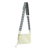 White multi compartment crossbody bag featuring a stylish patterned guitar strap