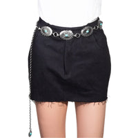 Black denim mini skirt styled with an ornate metallic oval chain belt and turquoise conchos