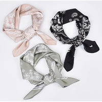 Three patterned silk scarves in pale pink, gray, and black with floral designs