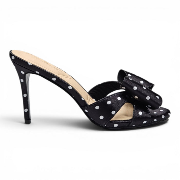Black high-heeled shoe with white polka dots on a white background