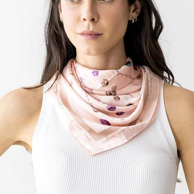 Light pink silk neck scarf with colorful polka dot pattern elegantly worn around the neck