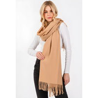 Camel-colored fringed oblong scarf draped over a white long-sleeved top