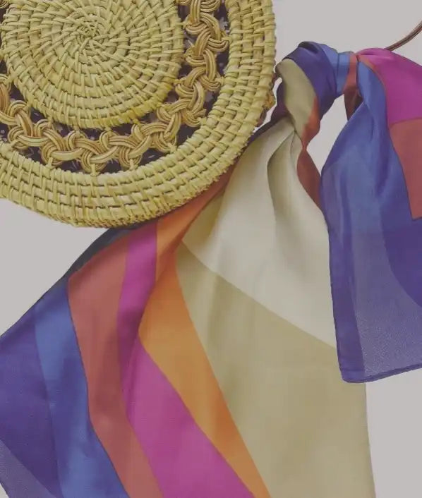 Straw sun hat with colorful striped silk scarf tied around its brim.