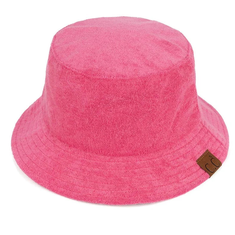 Bright pink terry cloth bucket hat with a brown label, perfect for stylish summer wear