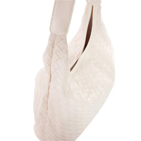 White ballet pointe shoe with satin ribbons beside a Woven Faux Leather Tote Bag