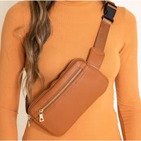 Brown leather zipper fanny pack bag with gold zipper worn across the chest